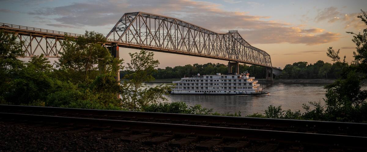 A steel bridge over a river with a white boat.