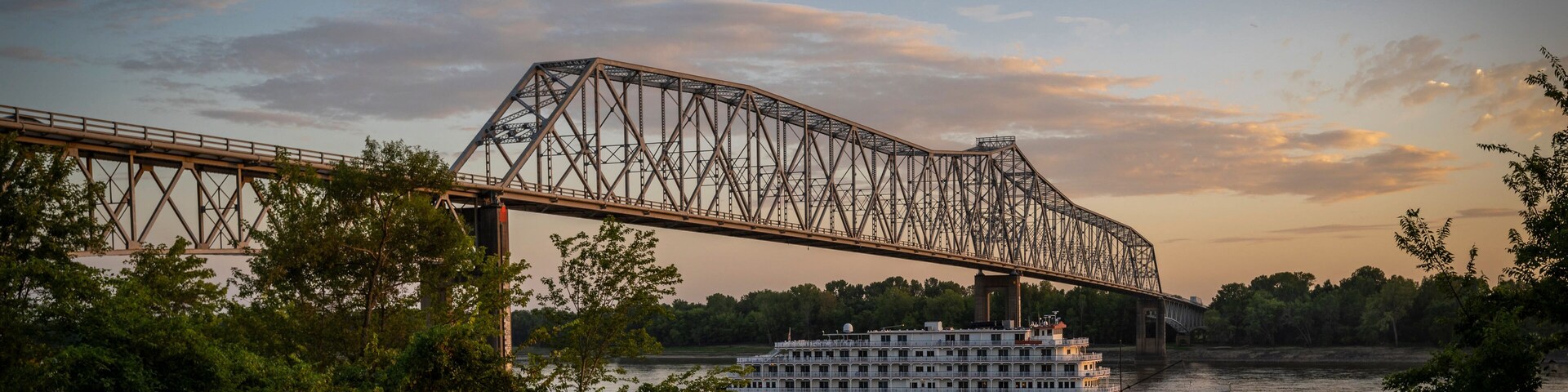 A steel bridge over a river with a white boat.
