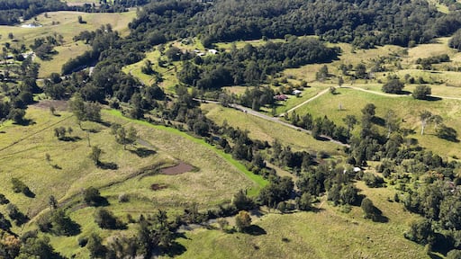 A rural landscape with rolling hills, a winding road, and scattered buildings.