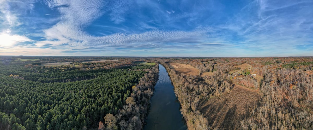 A river winding through a forested valley with a clear sky above.