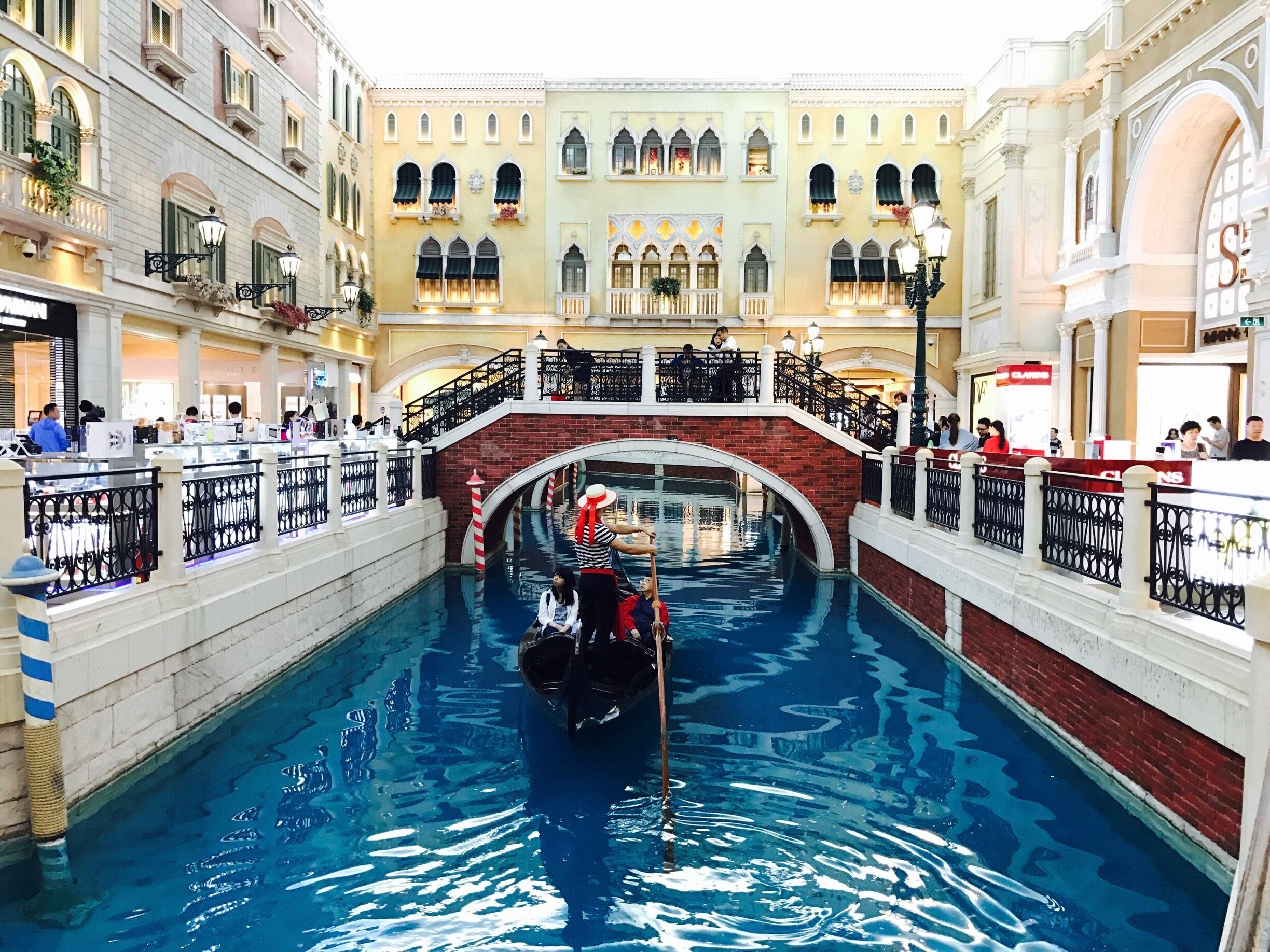 A Venetian-style indoor canal with a bridge, surrounded by ornate buildings and shops.