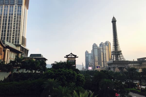 A cityscape with modern high-rise buildings, a replica of the Eiffel Tower, and traditional architecture.