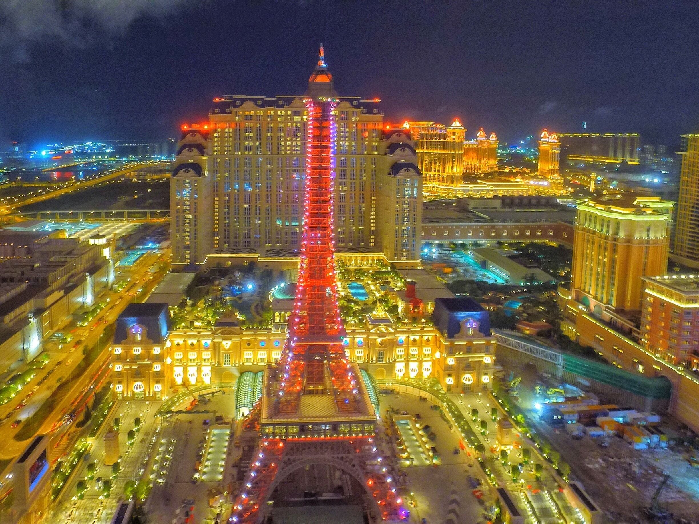 A brightly lit tower with red lights, surrounded by a cityscape at night.
