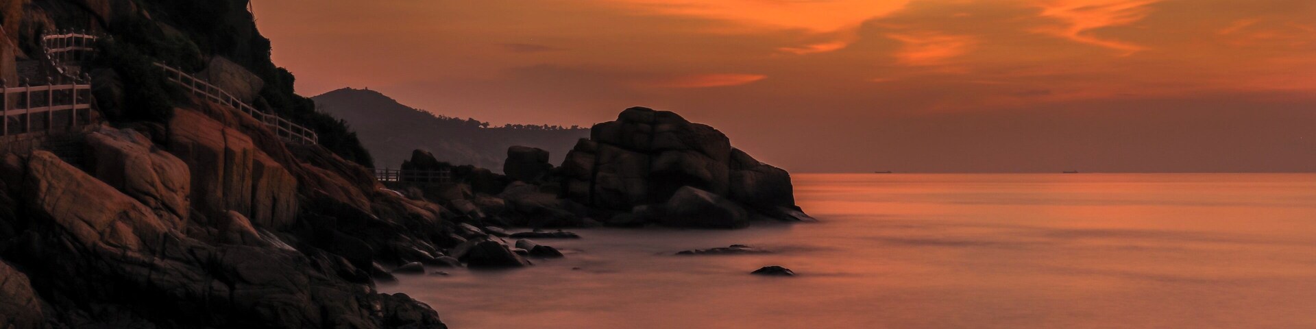 Un paisaje costero con acantilados rocosos y un mar tranquilo al atardecer.
