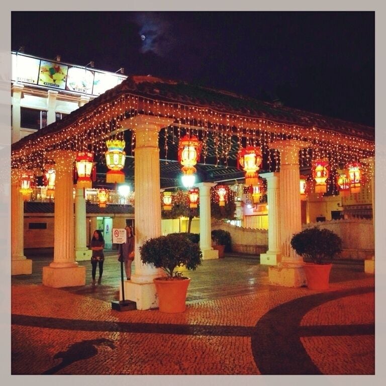 A building with a covered entrance decorated with string lights and traditional lanterns.