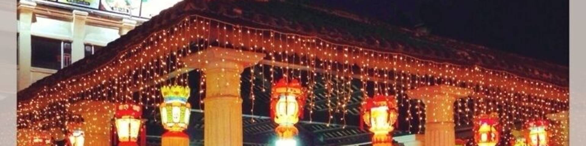 A building with a covered entrance decorated with string lights and traditional lanterns.