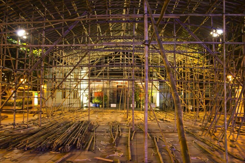 A construction site with scaffolding and bamboo poles.