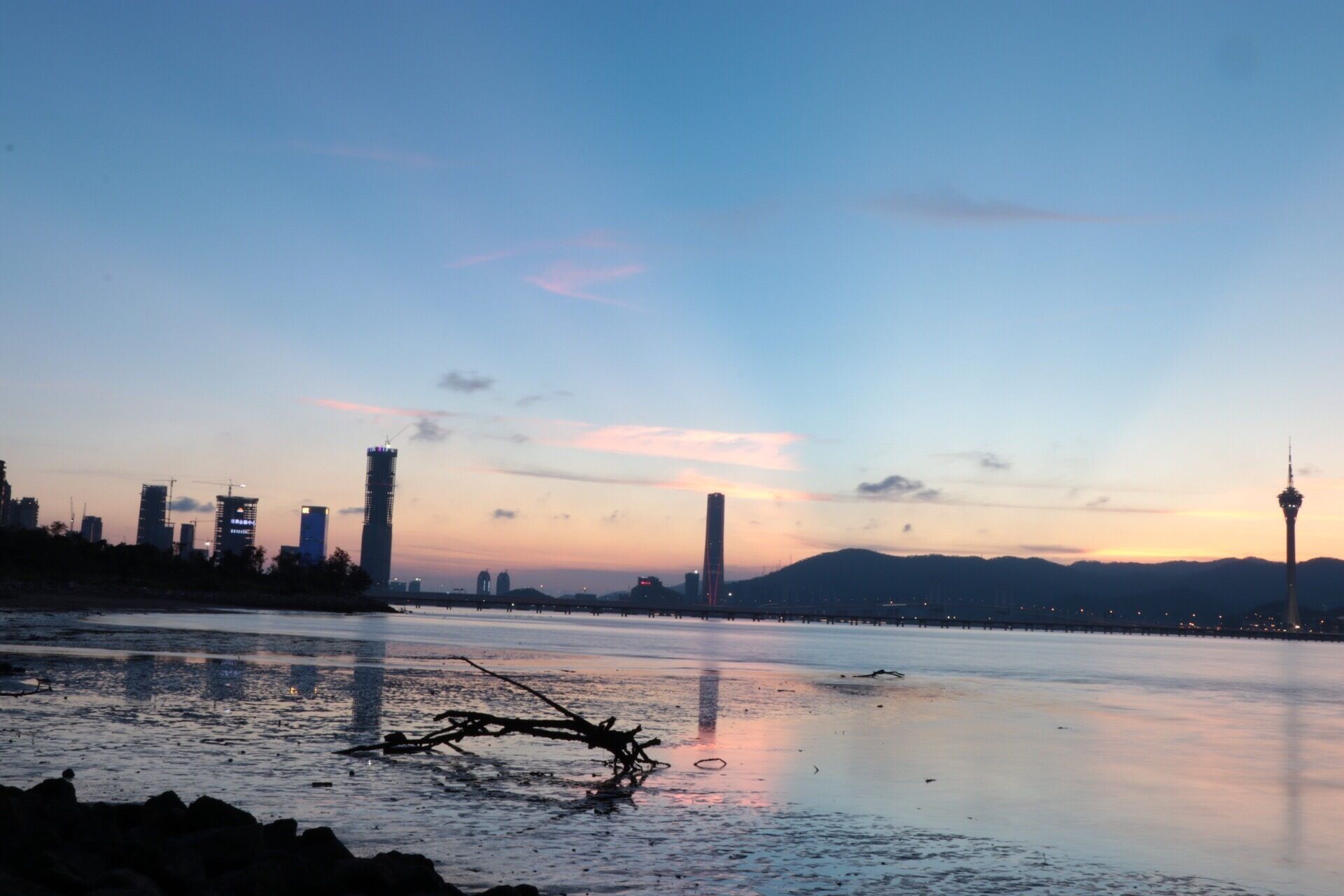 A river with a bridge, city skyline, and a tower in the distance.