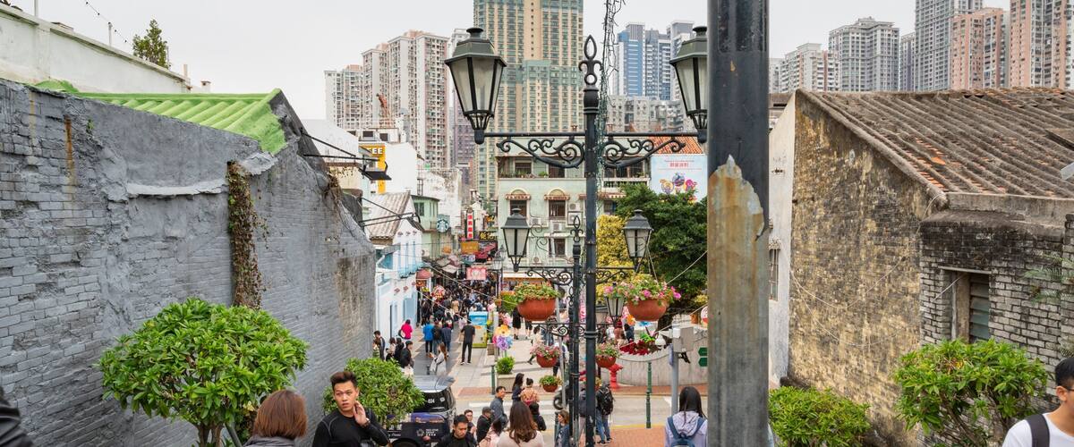 A bustling street with pedestrians, traditional buildings, and hanging flower pots.