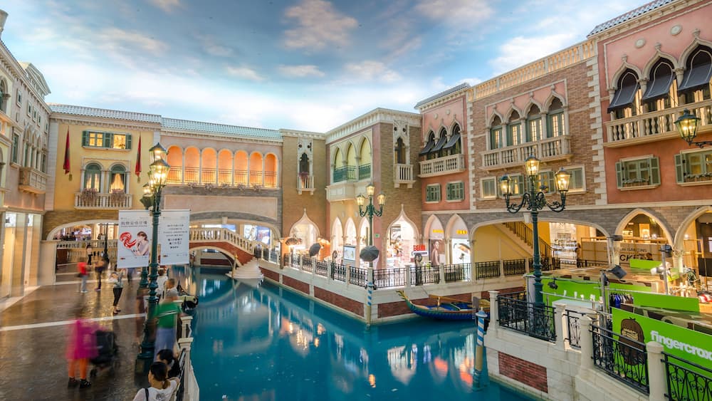 A Venetian-style indoor canal with gondolas, ornate buildings, and a shopping area.