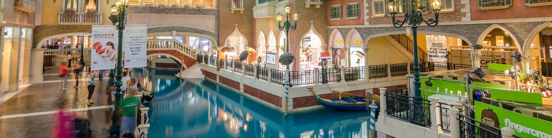 A Venetian-style indoor canal with gondolas, ornate buildings, and a shopping area.