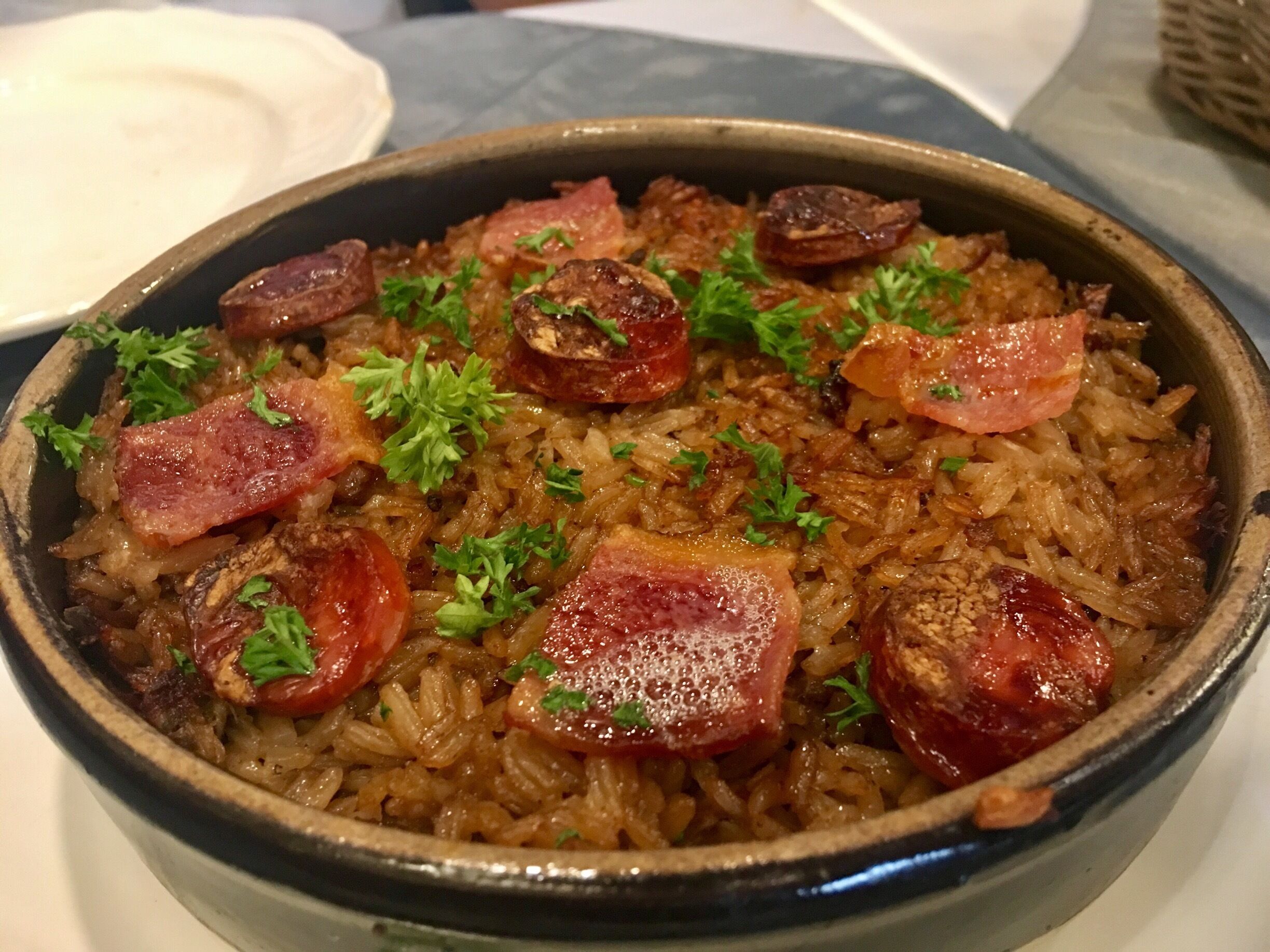 A dish of rice with sausage and parsley.