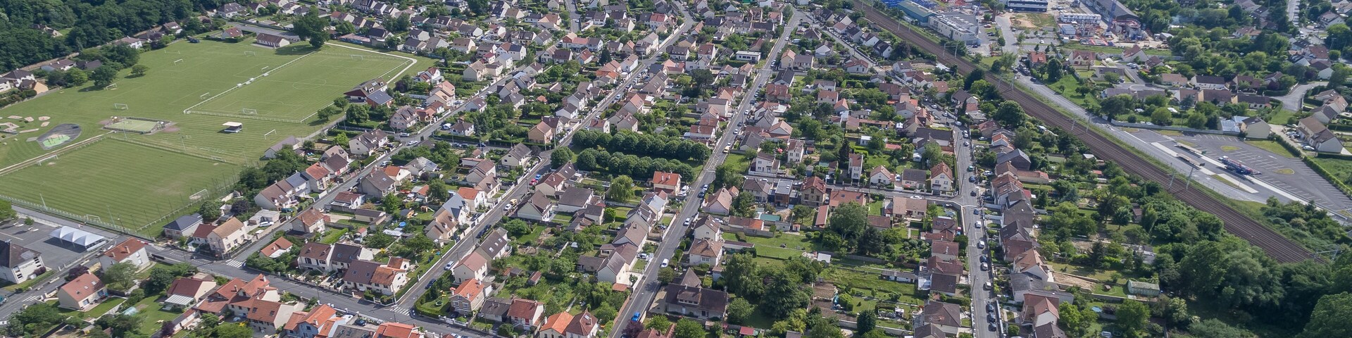 Vista aérea de una zona residencial con casas, calles y un amplio campo verde.