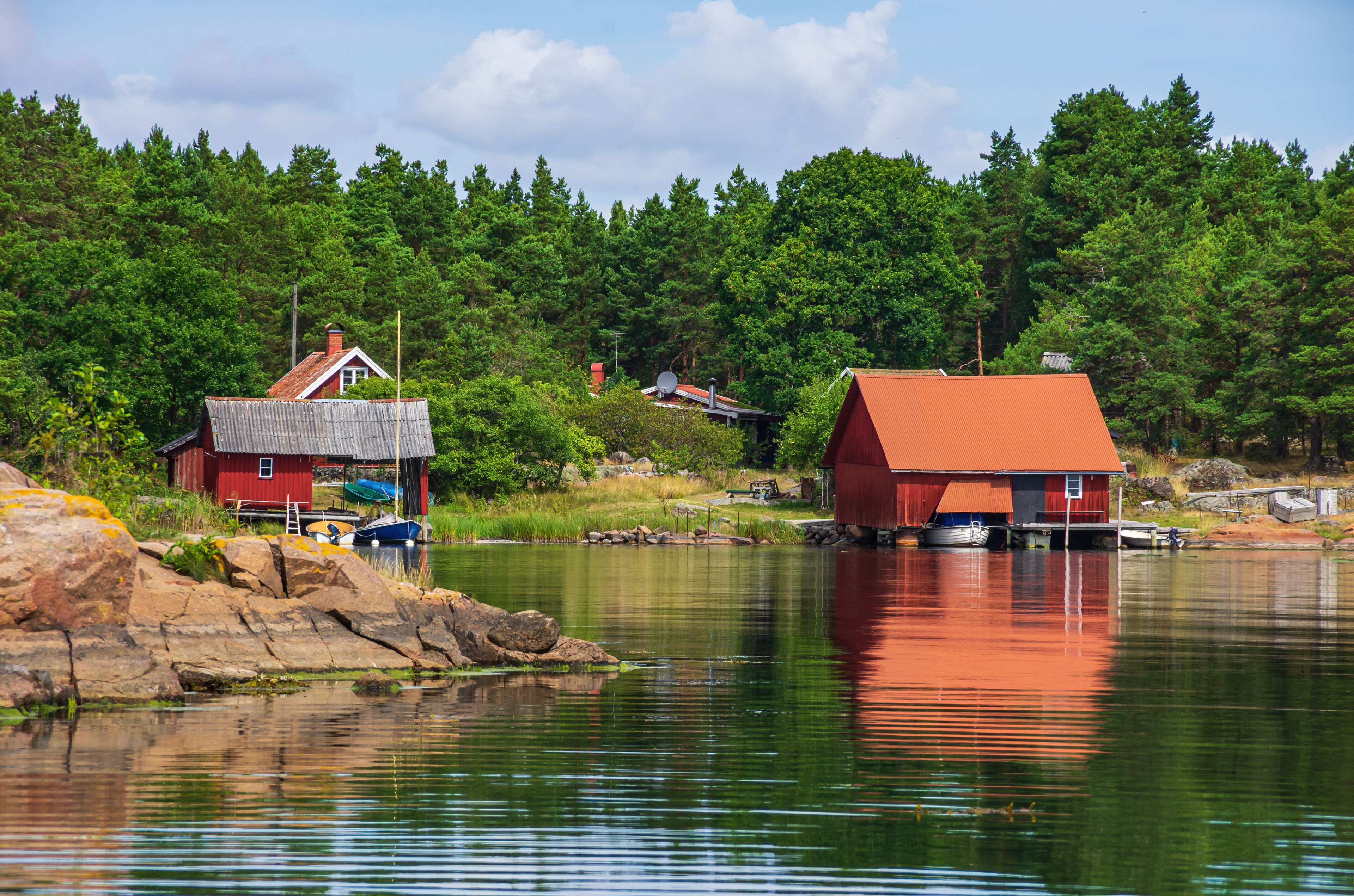 A calm lake with red buildings on stilts, surrounded by dense green forest.