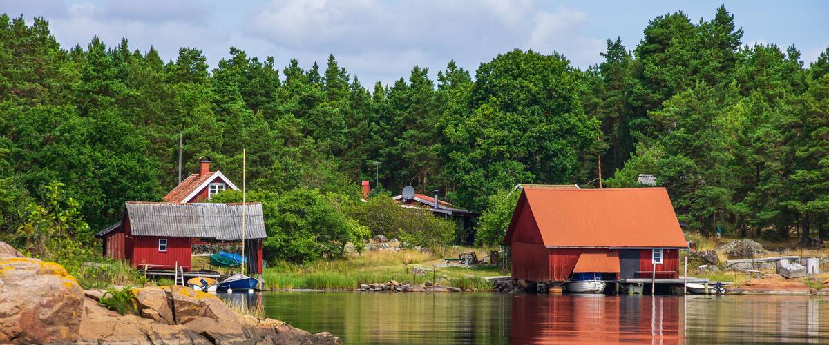 A calm lake with red buildings on stilts, surrounded by dense green forest.