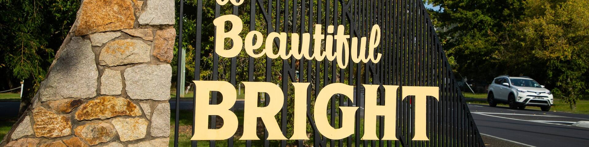 A stone wall with a metal gate and a sign that reads "Welcome to Beautiful BRIGHT."