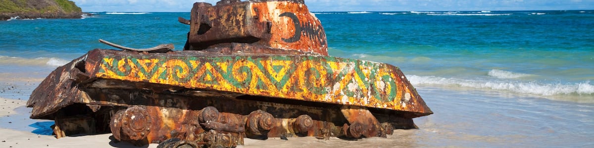 A rusted tank with colorful paint on a beach.