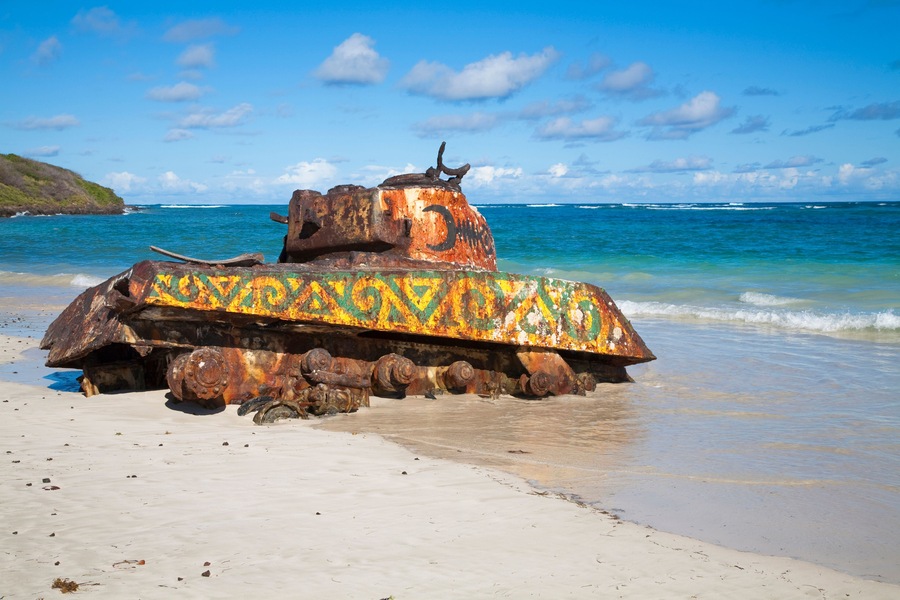 Een verroest tank met kleurrijke verf op het strand.