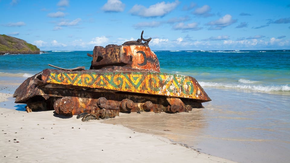 A rusted tank with colorful paint on a beach.