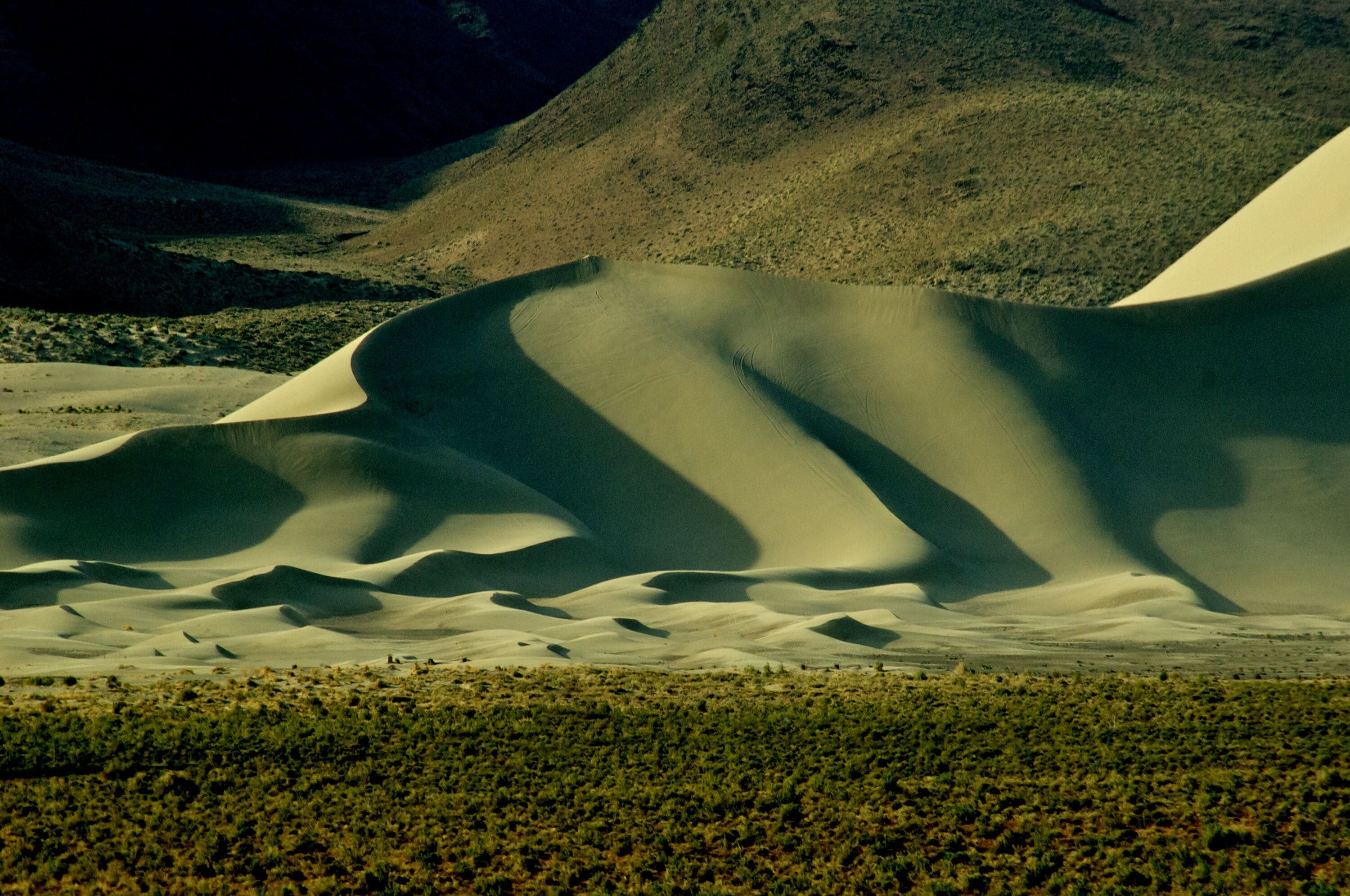 Dunas de areia com uma montanha ao fundo.