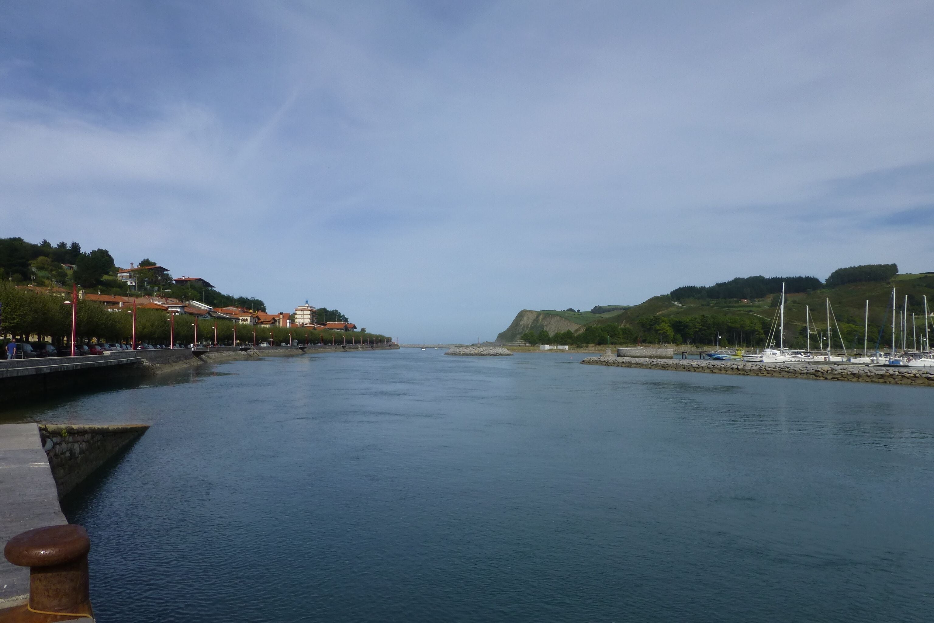 A calm river with boats, a bridge, and buildings on the left bank.