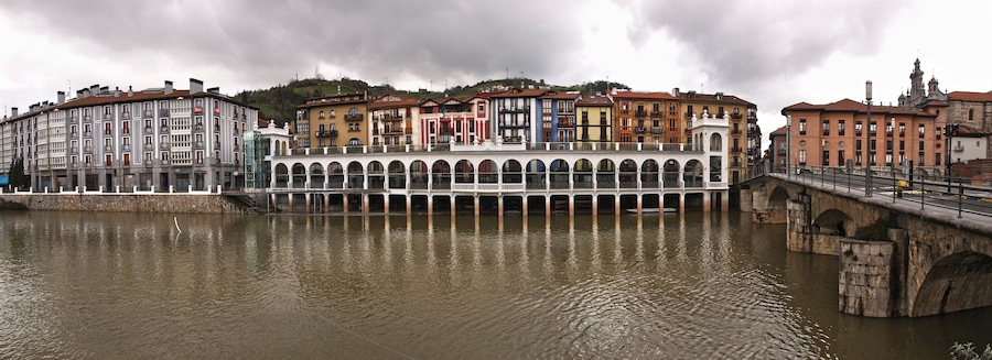 A riverside cityscape with historic buildings and a bridge.