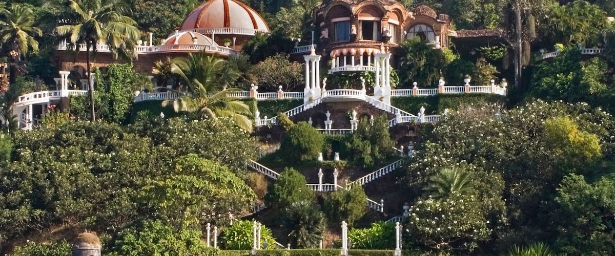 A coastal estate with a large dome, a bell tower, and a staircase leading up a hill.