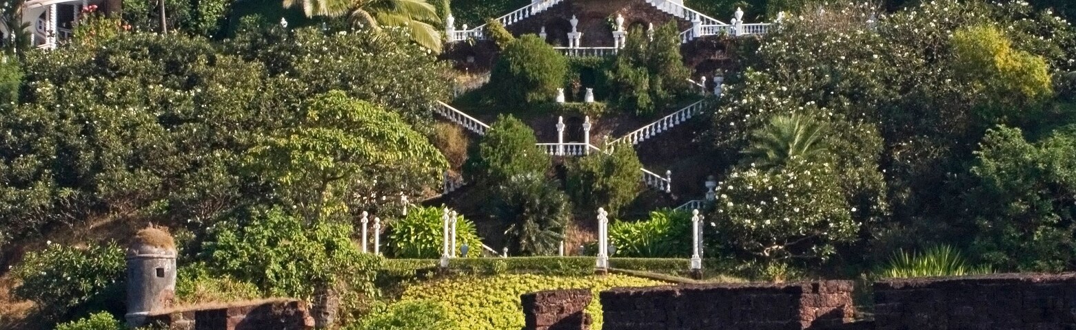 A coastal estate with a large dome, a bell tower, and a staircase leading up a hill.