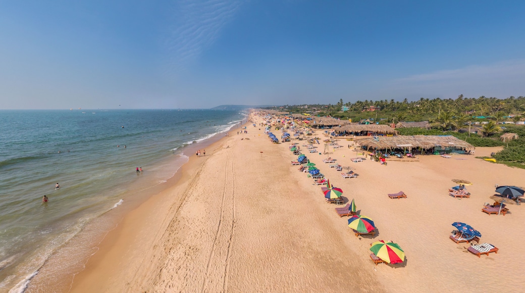 Une vaste plage de sable fin, bordĂ©e de cabanes aux toits de chaume et dâune rangĂ©e de parasols colorĂ©s.