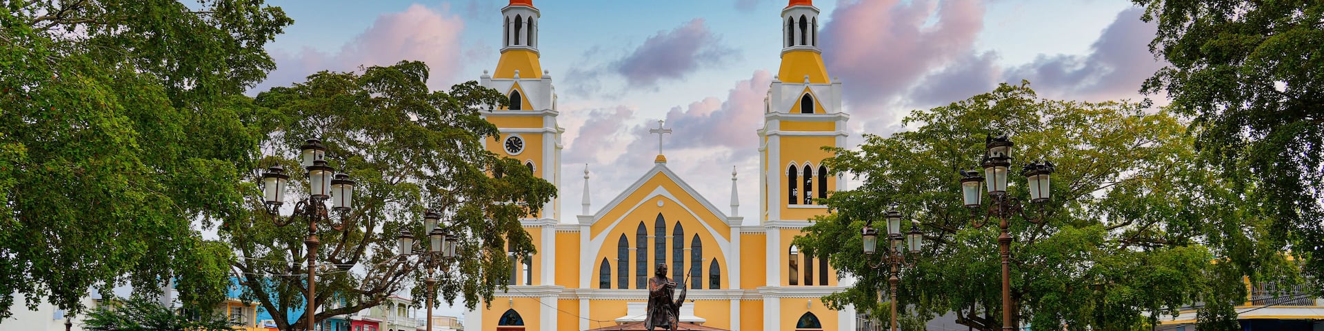 San Francisco de Asís Church overlooking the statue of Christopher Columbus in Aguada, Puerto Rico - Neogothic twin towers of a 20th century Catholic Church