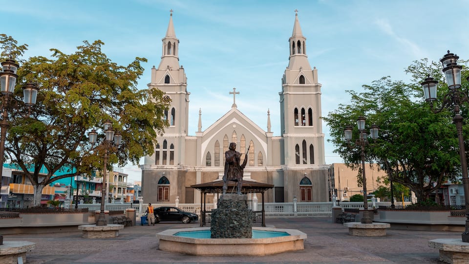 A church with two towers and a statue in front.