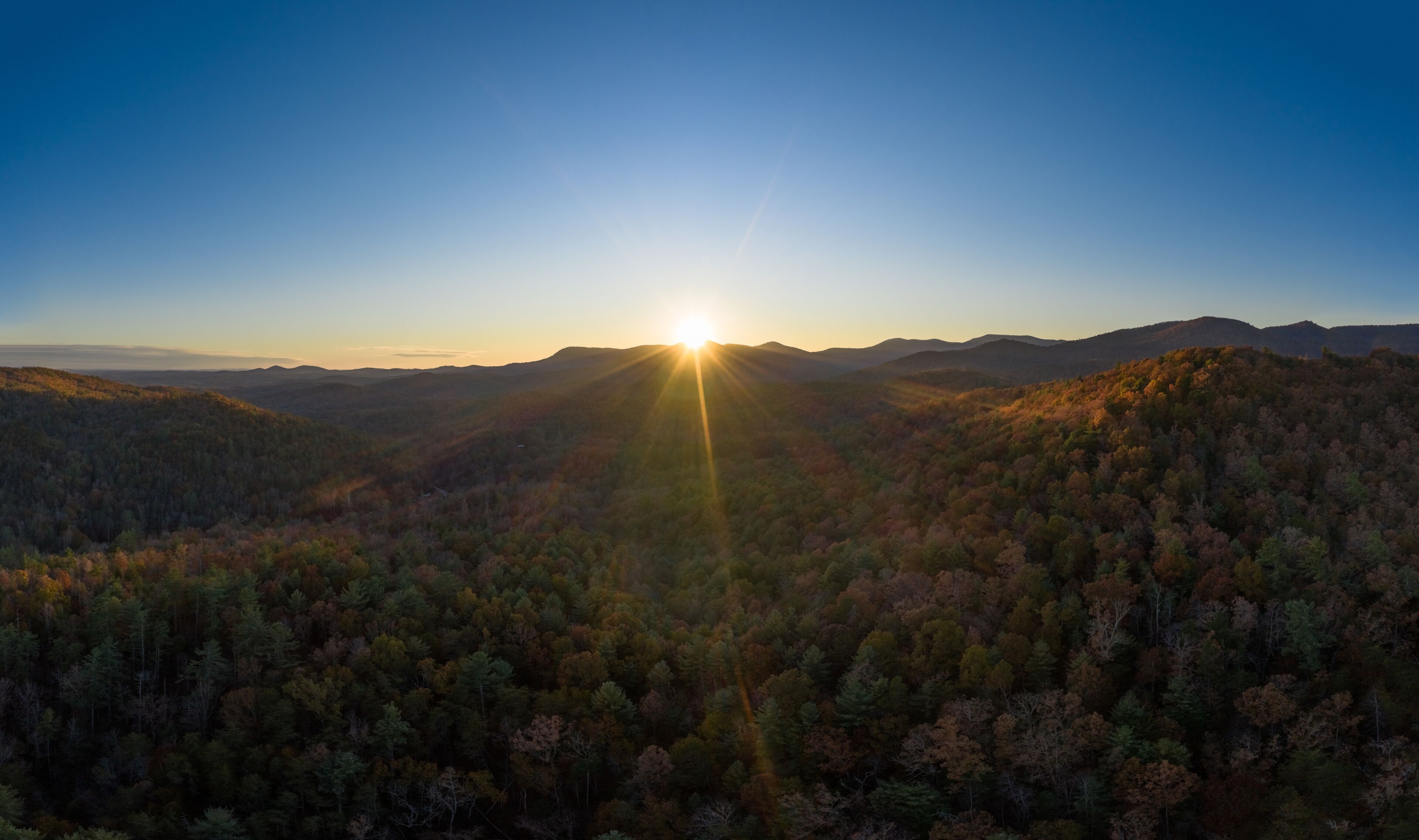 Aerial panoramic view of sunset with sun rays in Georgia Mountains during the fall