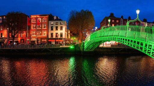 Ha'penny Bridge or Droichead na Life, refurbished 19th-century cast-iron span illuminated in green at night over River Liffey, Dublin, Ireland.