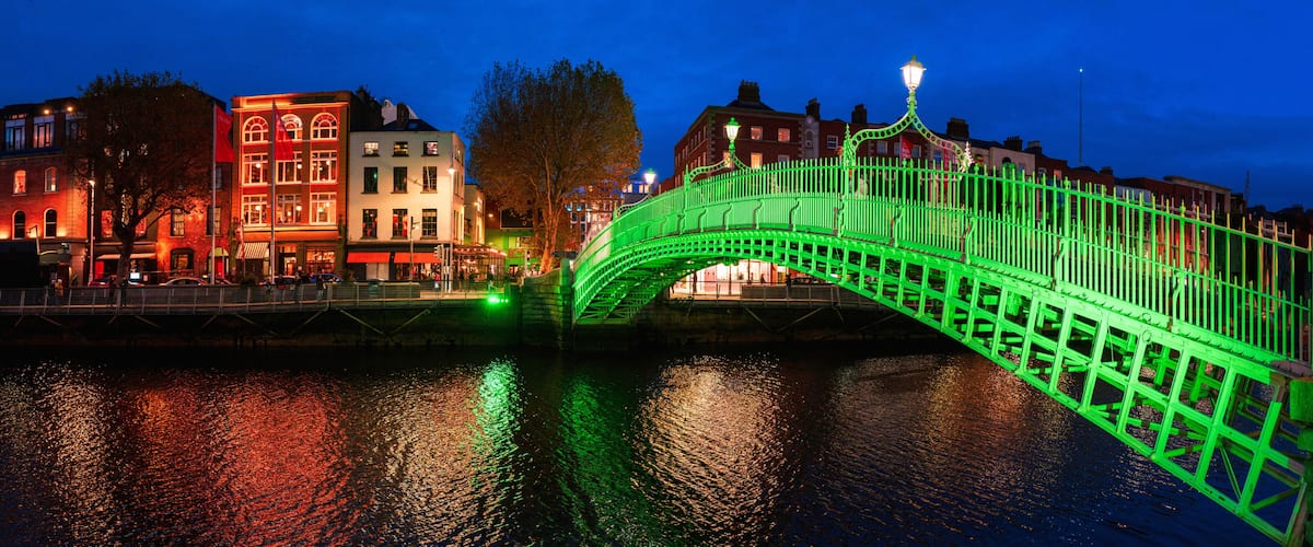 A green-lit bridge over water with buildings on either side.