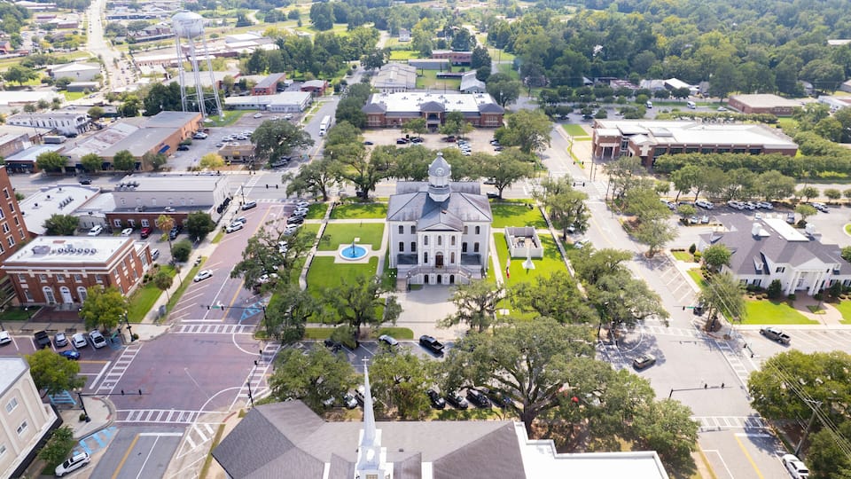 An aerial view of a town with a prominent church, a water tower, and various buildings.