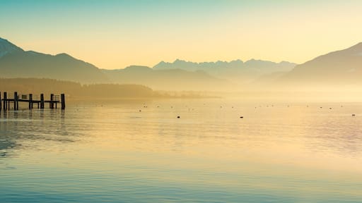 Een kalm meer met bergen op de achtergrond en een houten steiger die het water in reikt.