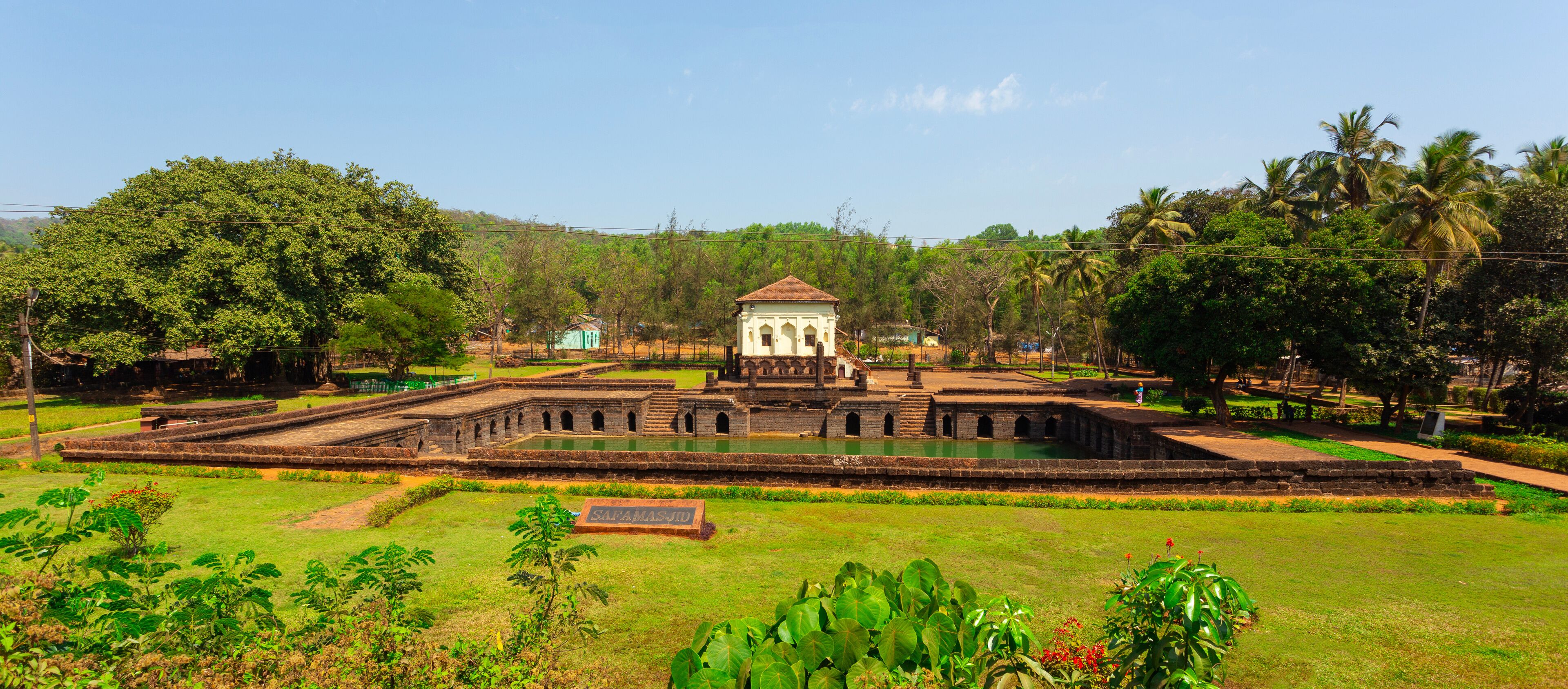 A historical site with a central tower, surrounding walls, and a water feature.