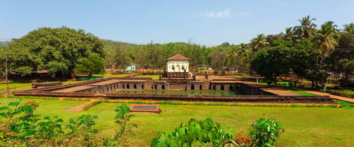 A historical site with a central tower, surrounding walls, and a water feature.