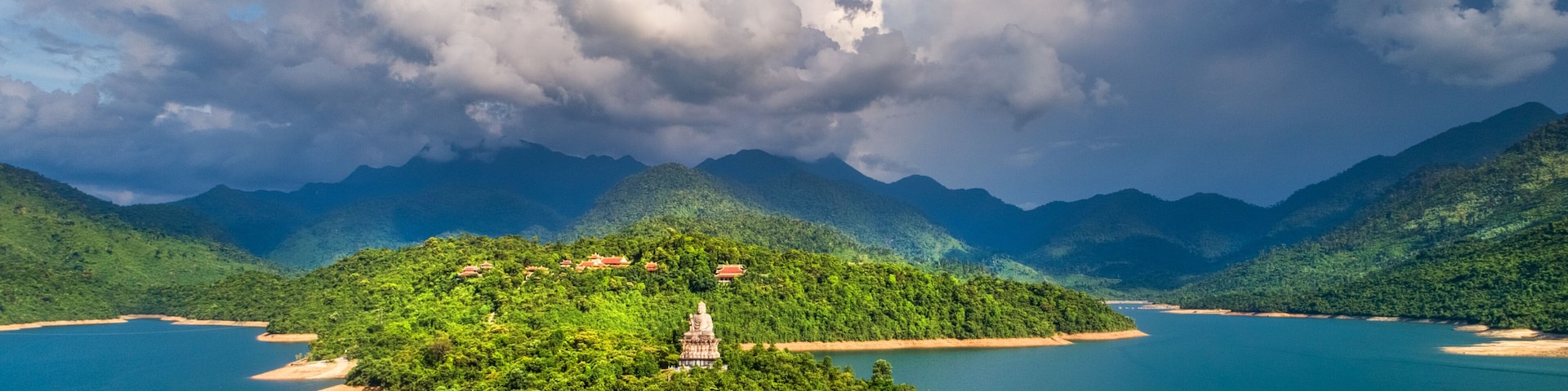 Una isla verde exuberante con un templo en el centro, rodeada por un lago azul tranquilo y montañas al fondo.