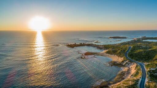 Scenic drive passing near ocean coastline and Beachport town at sunset - wide aerial panorama