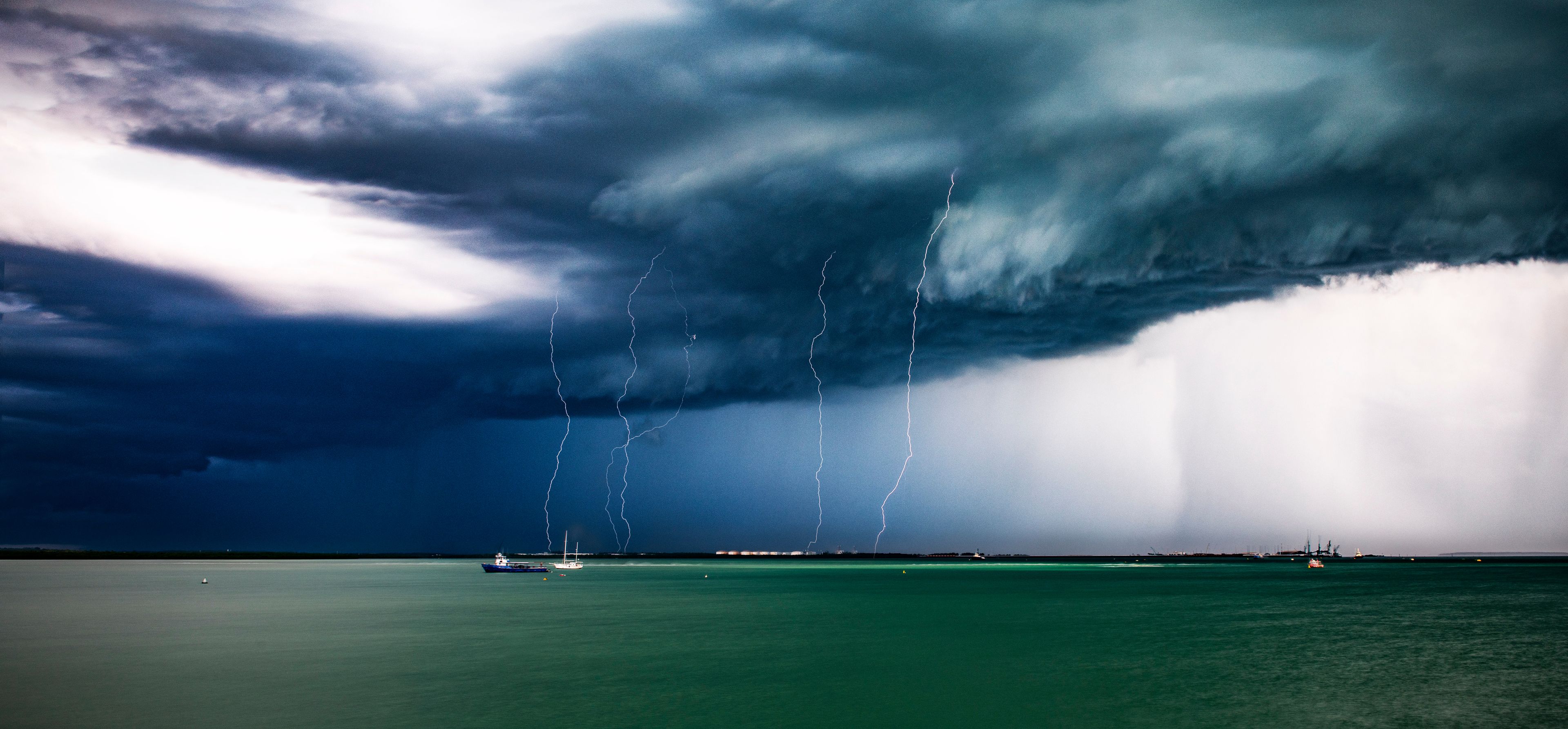 A stormy sea with lightning and a boat in the distance.