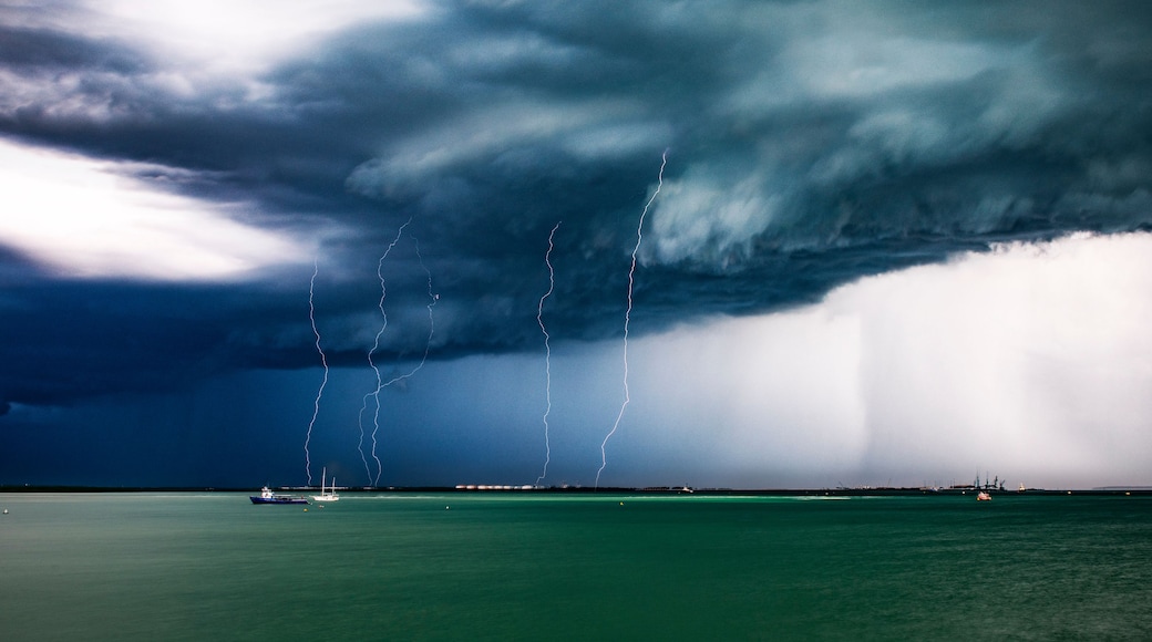 A stormy sea with lightning and a boat in the distance.