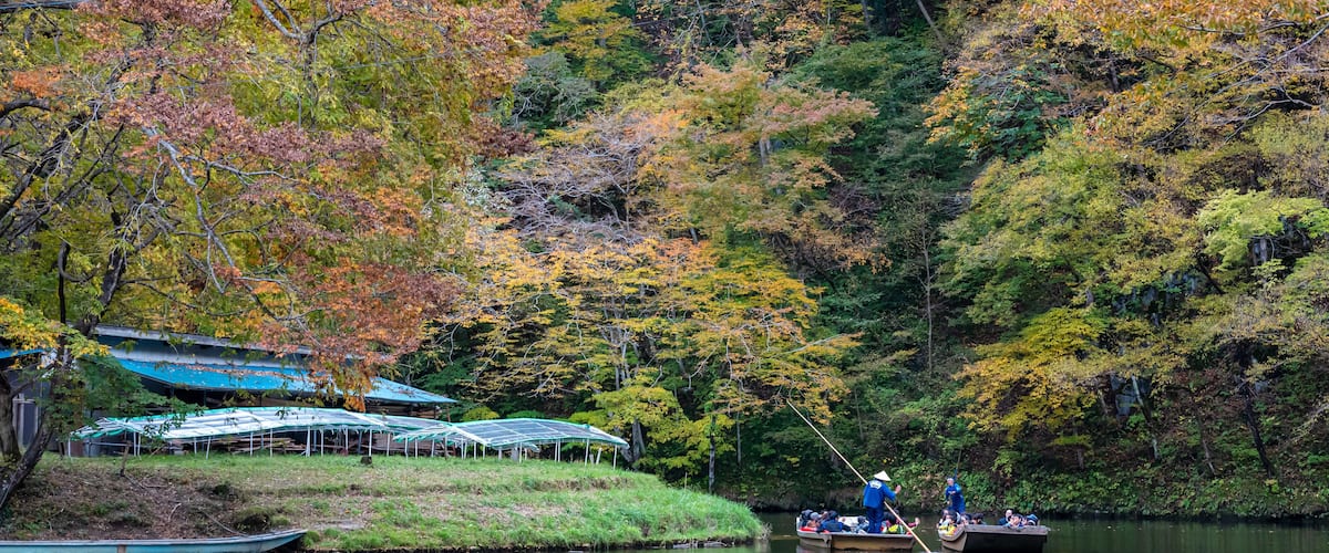 A serene river with boats, surrounded by autumn foliage.