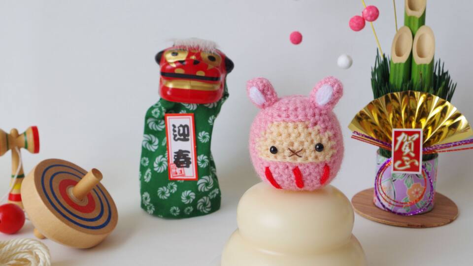 A spinning top, a small bottle with a label, a crocheted bunny, and a fan with decorative elements.