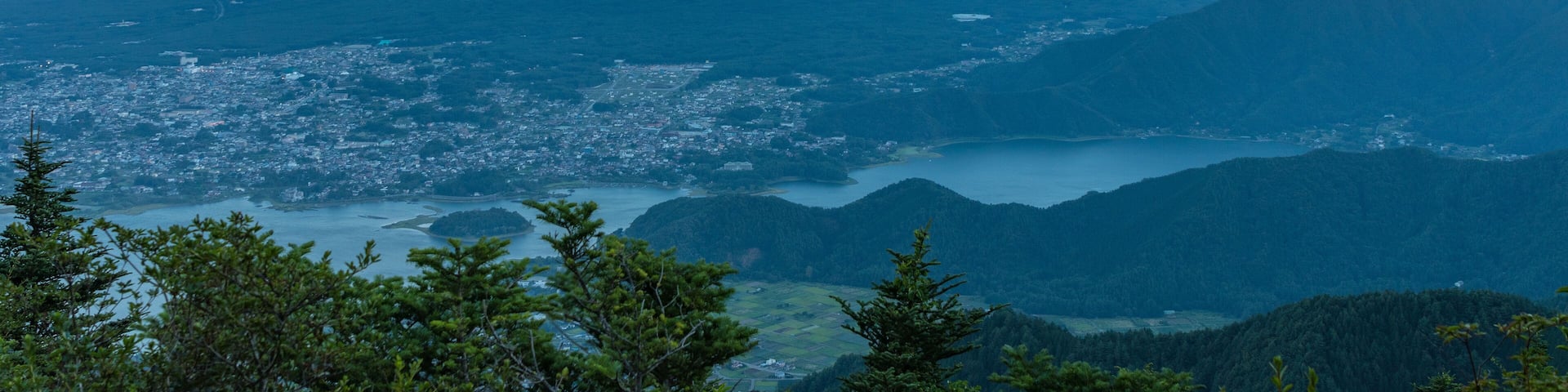A mountain with a conical shape, a valley with a town, and a body of water.