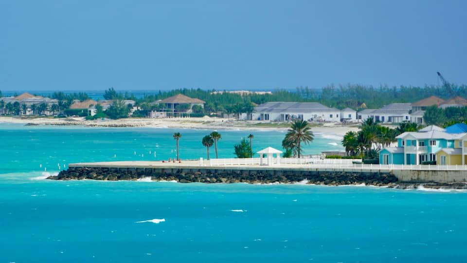 A coastal area with a pier, beach houses, and a clear blue sea.