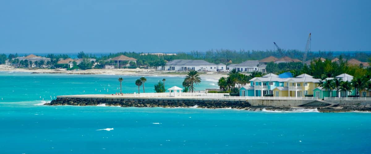A coastal area with a pier, beach houses, and a clear blue sea.