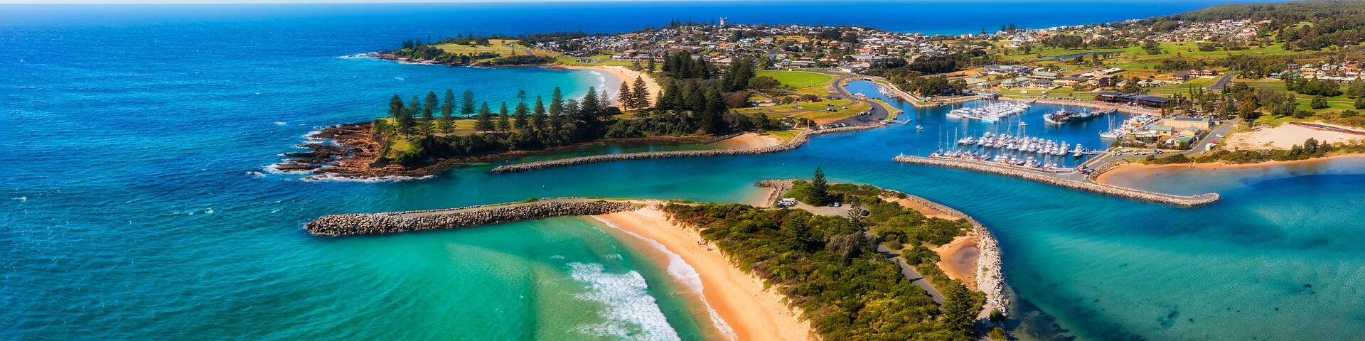 A coastal town with a marina, sandy beaches, and a clear blue sea.