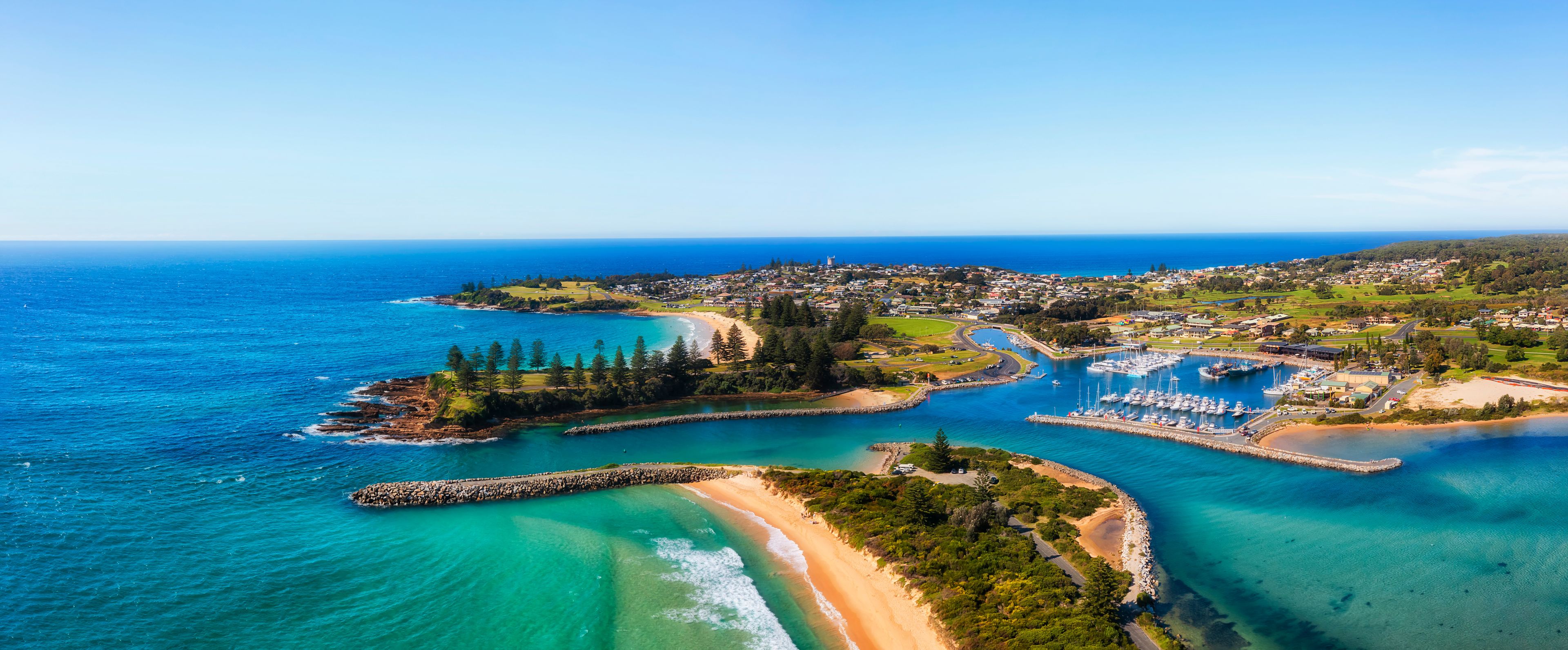 A coastal town with a marina, sandy beaches, and a clear blue sea.