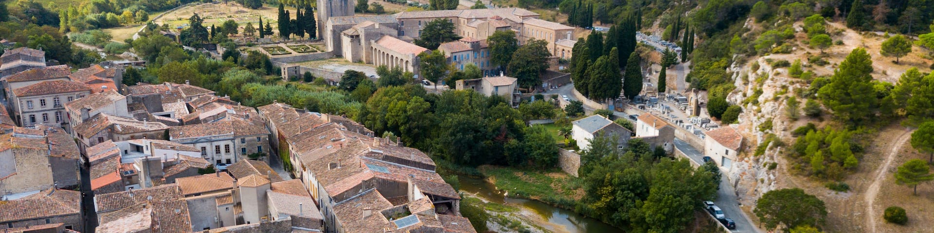 A historic town with terracotta-roofed buildings, a river, and a stone bridge.